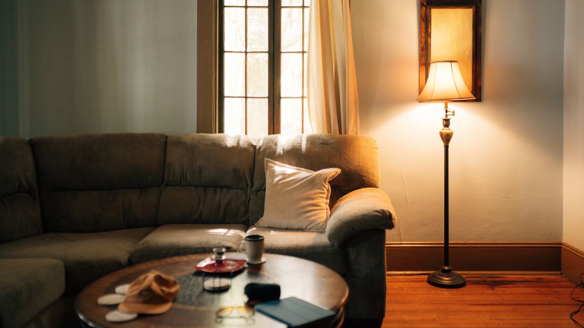 A quiet living room at dusk with one lamp lit beside the sofa